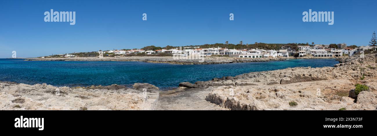 Fotografía panorámica de la cala de Biniancolla en la isla de Menorca, que ofrece un pintoresco paisaje de típicas casas blancas. España Stock Photo