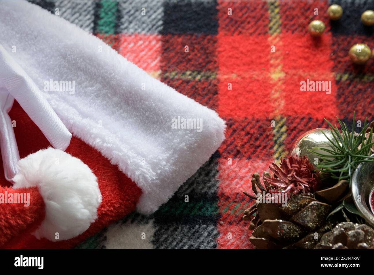 Christmas background - candle, Santa hat, white gloves on a winter red plaid Stock Photo