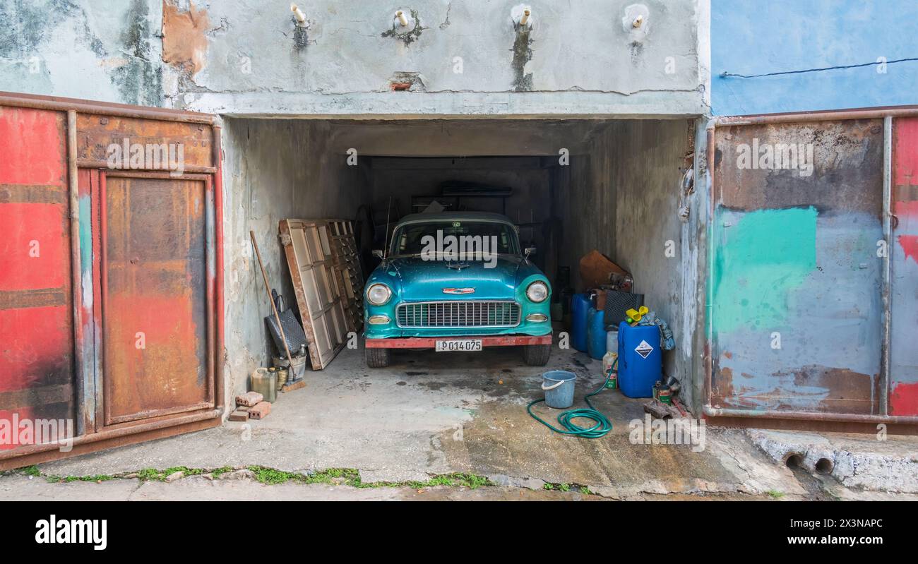 A classic old American car which is used as a taxi being washed in a backstreet garage in the Old Town, Trinidad, Cuba Stock Photo