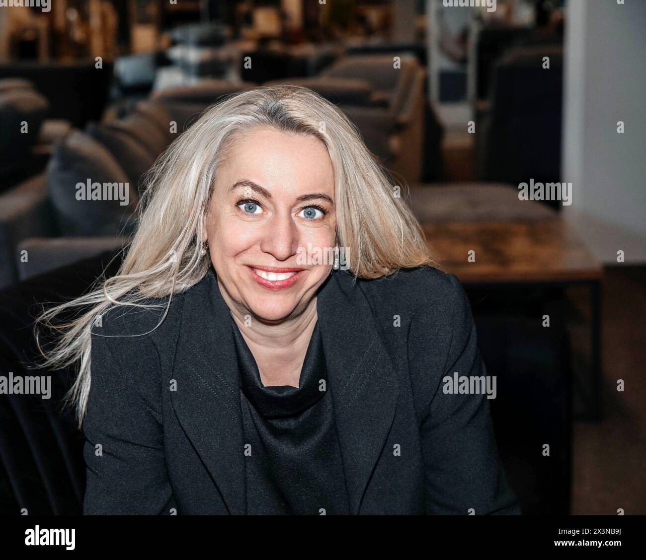 Confident Professional Woman with Platinum Blonde Hair in a Chic Black Blazer Smiling at