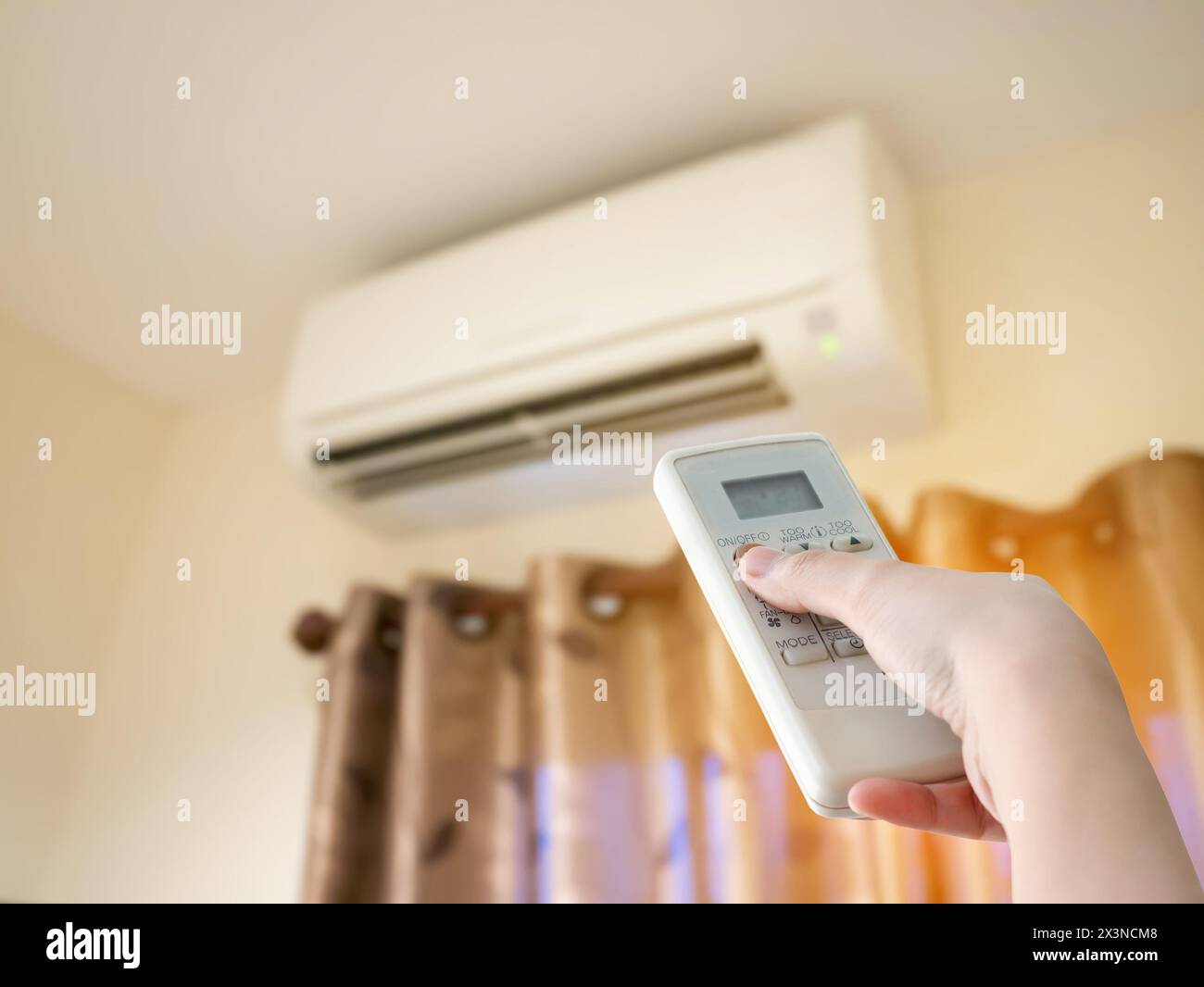 Hand hold remote control directed on the air conditioner Stock Photo