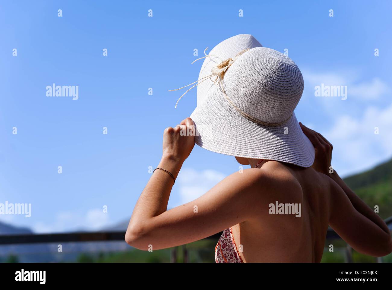 Rear view of a woman wearing a white hat is standing in front of a blue ...