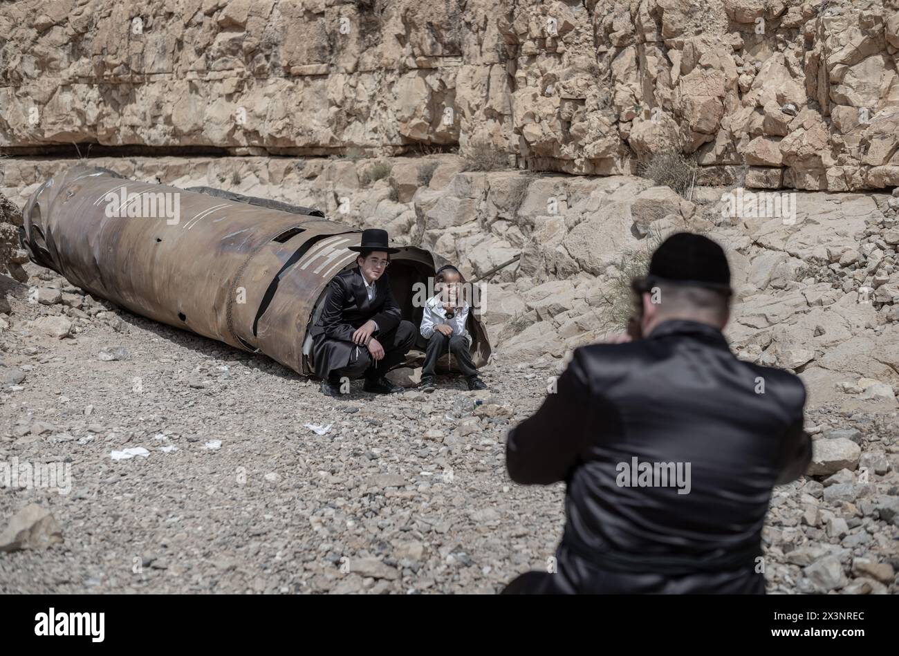 Arad, Israel. 28th Apr, 2024. Israeli Orthodox Jews get their picture taken with parts of an Iranian rocket that were left in the desert near southern Israeli city of Arad. Credit: Ilia Yefimovich/dpa/Alamy Live News Stock Photo