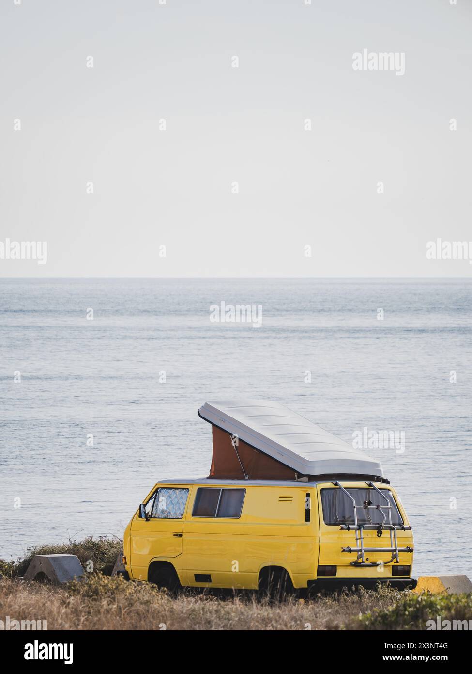 Yellow vintage camper van with pop-up roof parked by the sea Stock ...