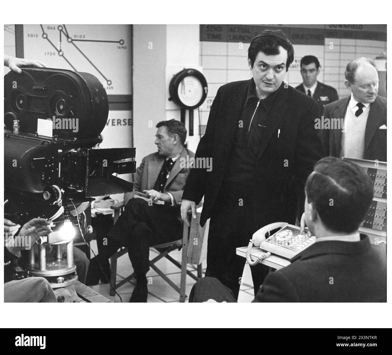 Director STANLEY KUBRICK talks to PETER SELLERS in costume for his role as Group Captain Lionel Mandrake on the set of DR. STRANGELOVE or : How I Learned to Stop Worrying and Love the Bomb 1964.Sitting behind him is STERLING HAYDEN who played Brigadier General Jack D. Ripper. Book PETER GEORGE Screenplay STANLEY KUBRICK, TERRY SOUTHERN and PETER GEORGE Production Design KEN ADAM Hawk Films / Columbia Pictures Stock Photo
