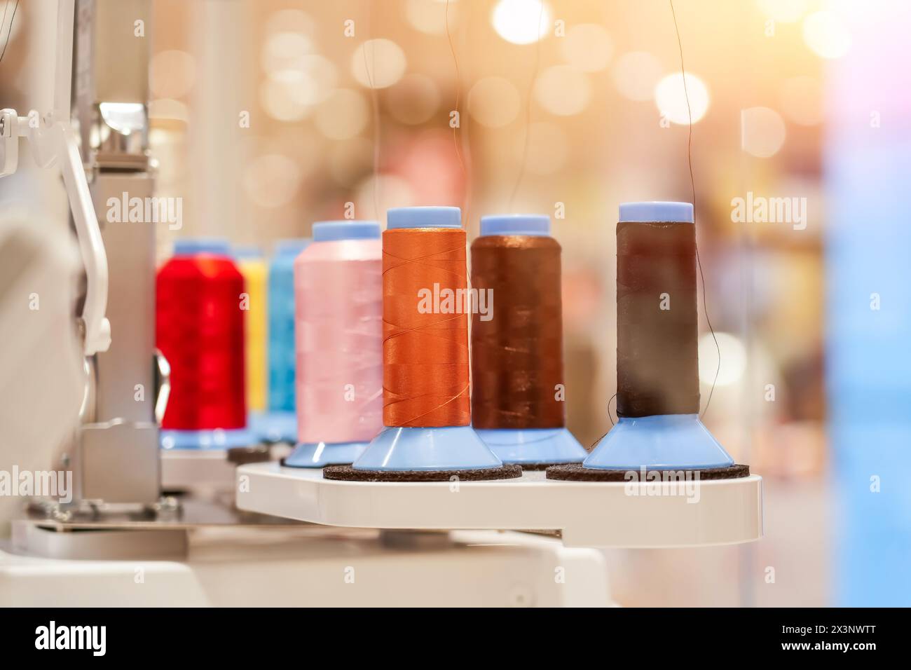 spools of colored thread installed on an automatic digital sewing machine. Stock Photo