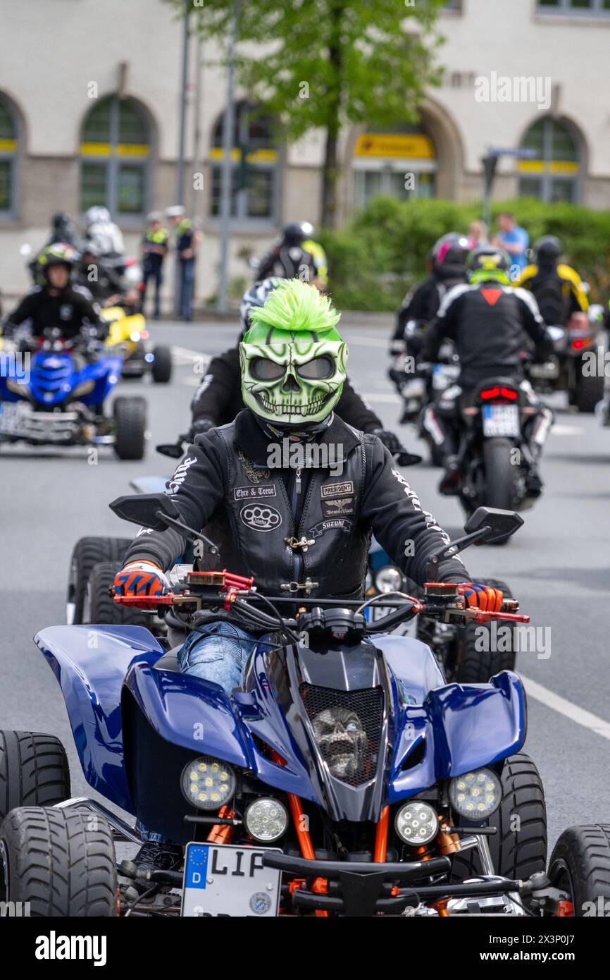 Kulmbach, Germany. 28th Apr, 2024. A quad biker with a green skull mask rides among numerous other motorcycles. Every year at the end of April, thousands of motorcyclists come together in Kulmbach for the biggest biker meeting in southern Germany to kick off the motorcycle season. They ride through the town together in a parade. Credit: Pia Bayer/dpa/Alamy Live News Stock Photo