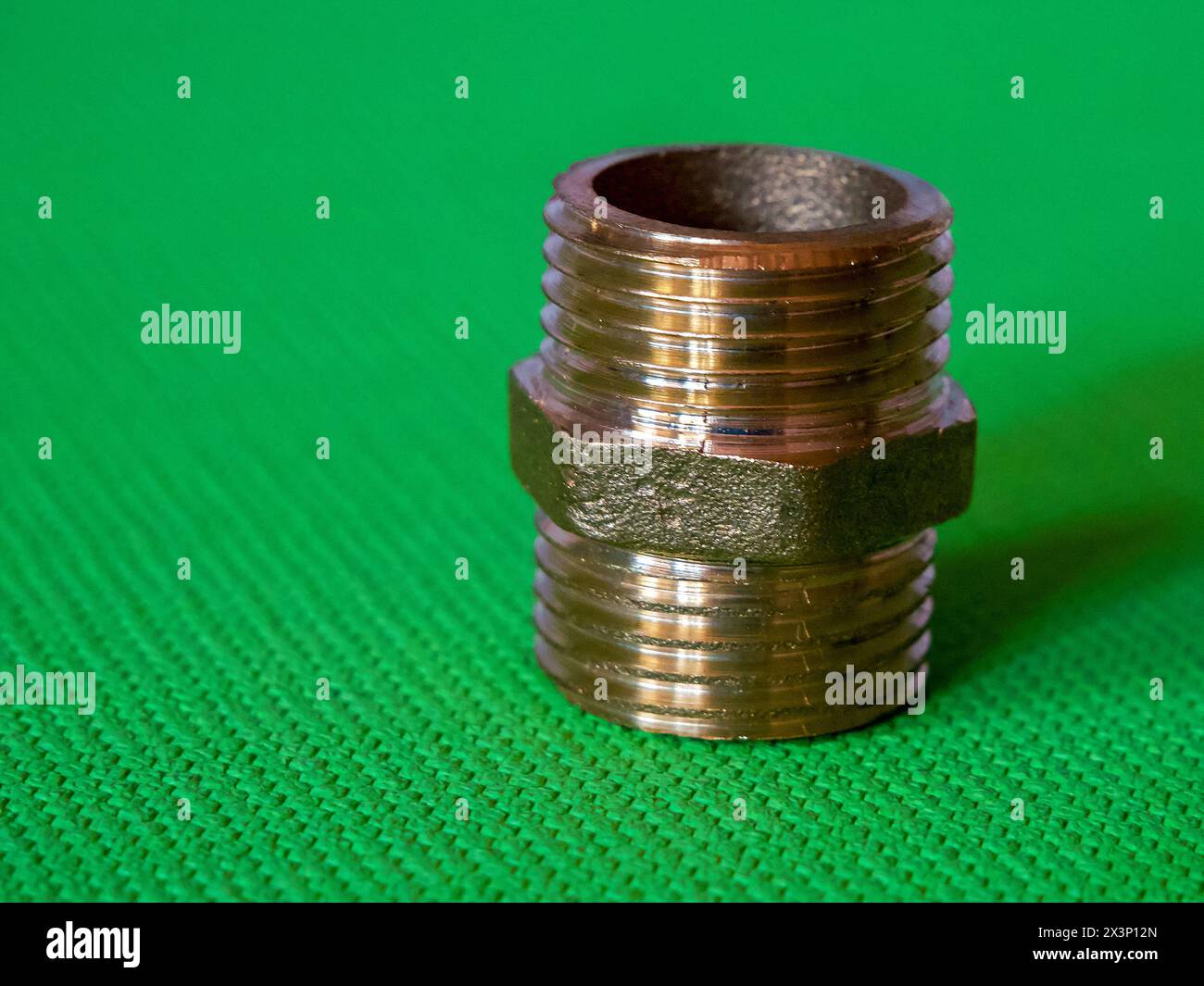 Brass Fitting on Green. A brass fitting with threading and hexagonal