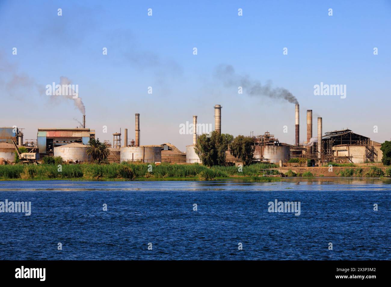 Smoke pollution belching from factory chimneys, Kom Elemeir sugar mill on the banks of the River Nile, Edfu, Aswan, Egypt Stock Photo
