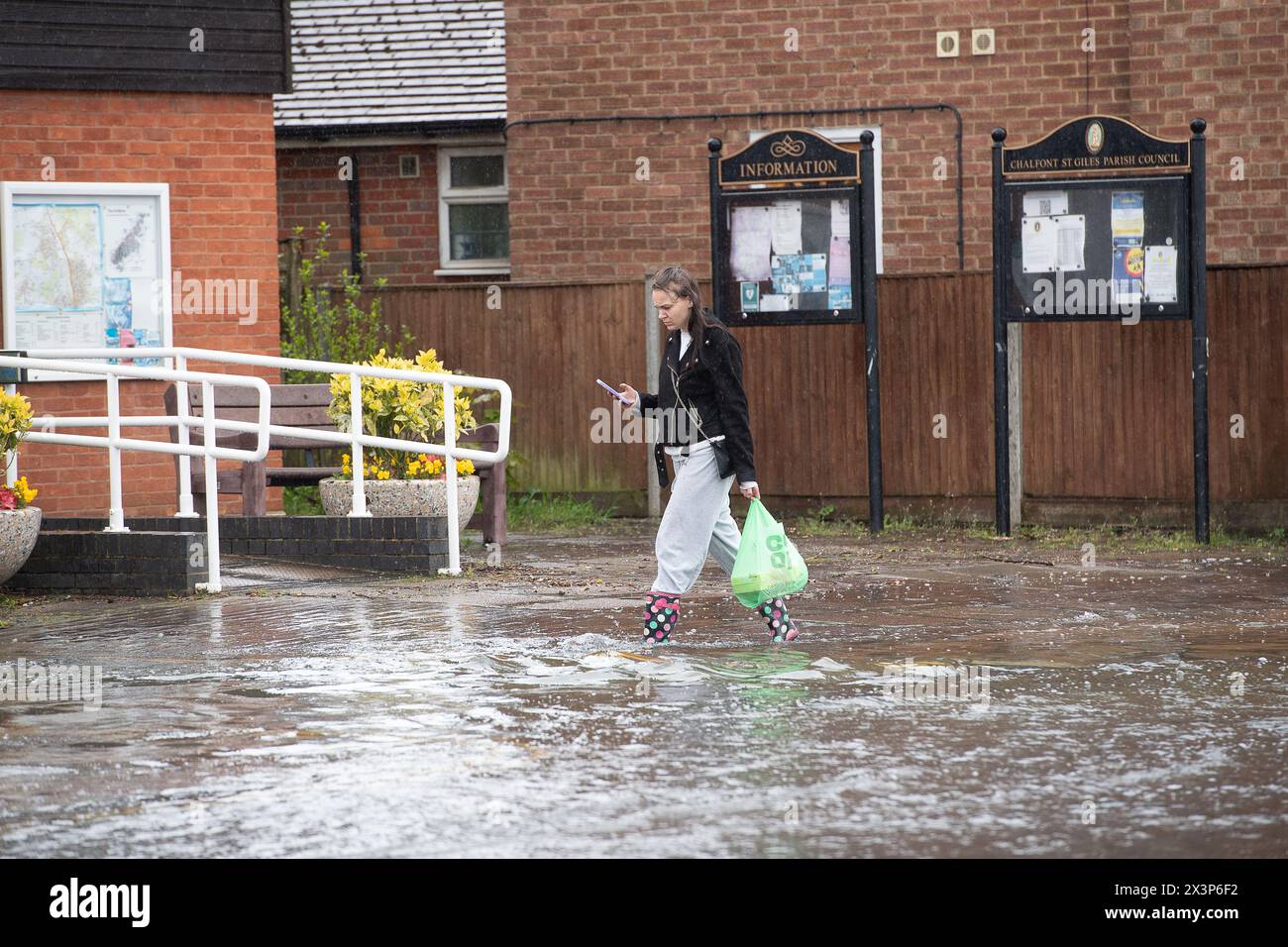 Chalfont St Giles, Buckinghamshire, UK. 28th April, 2024. A pedestrian walks through floodwater. Parts of the village of Chalfont St Giles in Buckinghamshire was flooded again today after heavy overnight rain. There are ongoing issues with groundwater flooding across the Chalfonts. Credit: Maureen McLean/Alamy Live News Stock Photo