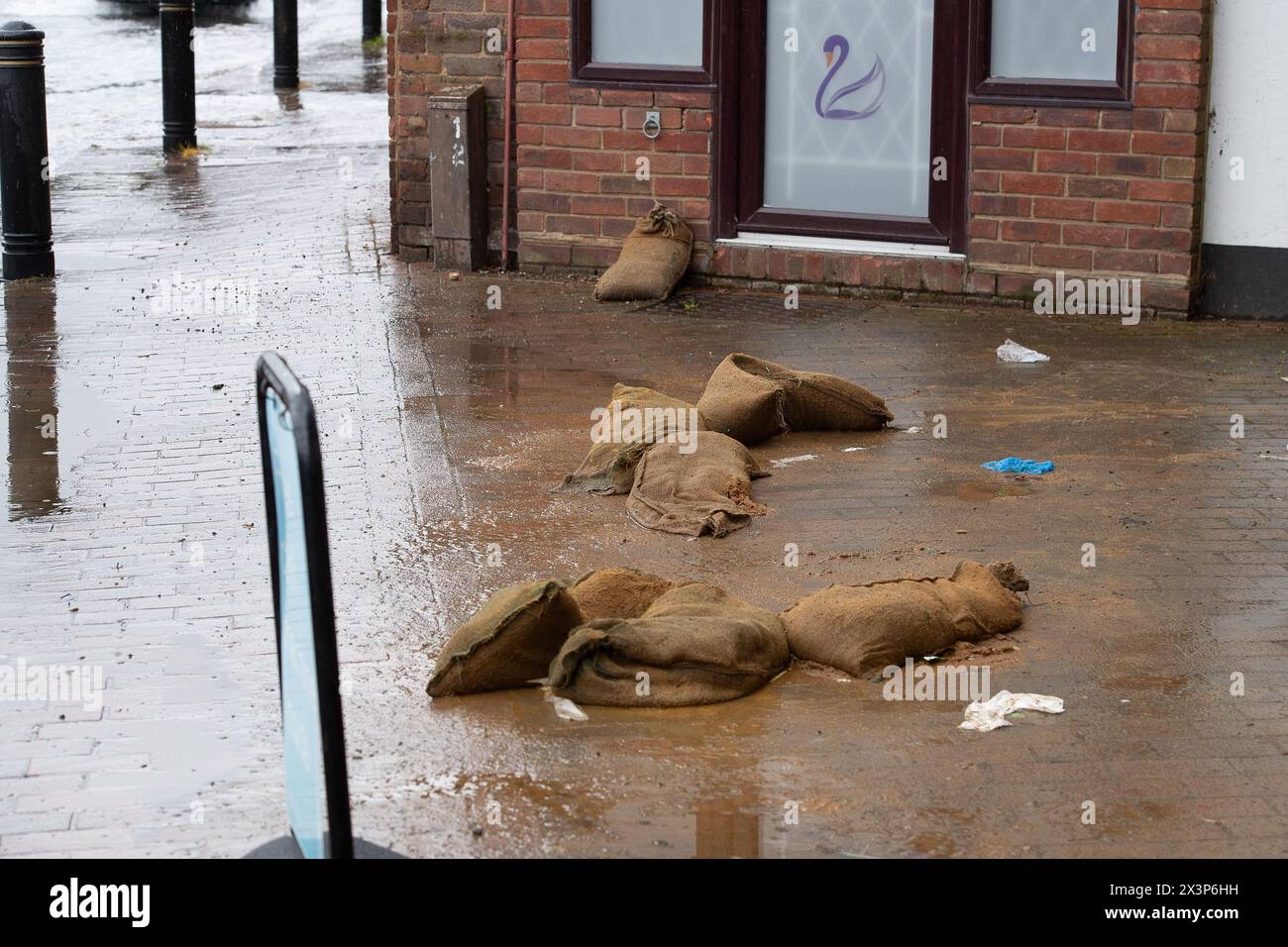 Chalfont St Giles, Buckinghamshire, UK. 28th April, 2024. Sandbags scattered outside a shop. Parts of the village of Chalfont St Giles in Buckinghamshire was flooded again today after heavy overnight rain. There are ongoing issues with groundwater flooding across the Chalfonts. Credit: Maureen McLean/Alamy Live News Stock Photo