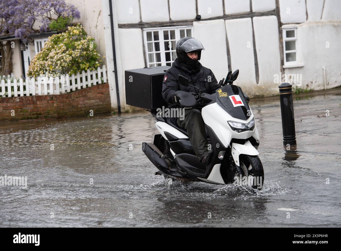 Chalfont St Giles, Buckinghamshire, UK. 28th April, 2024. A motorcyclist driving through floodwater. Parts of the village of Chalfont St Giles in Buckinghamshire was flooded again today after heavy overnight rain. There are ongoing issues with groundwater flooding across the Chalfonts. Credit: Maureen McLean/Alamy Live News Stock Photo