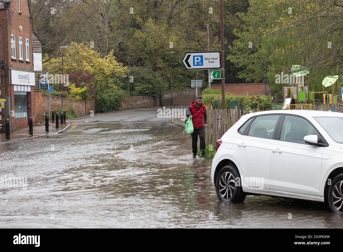Chalfont St Giles, Buckinghamshire, UK. 28th April, 2024. A pedestrian walks through floodwater. Parts of the village of Chalfont St Giles in Buckinghamshire was flooded again today after heavy overnight rain. There are ongoing issues with groundwater flooding across the Chalfonts. Credit: Maureen McLean/Alamy Live News Stock Photo