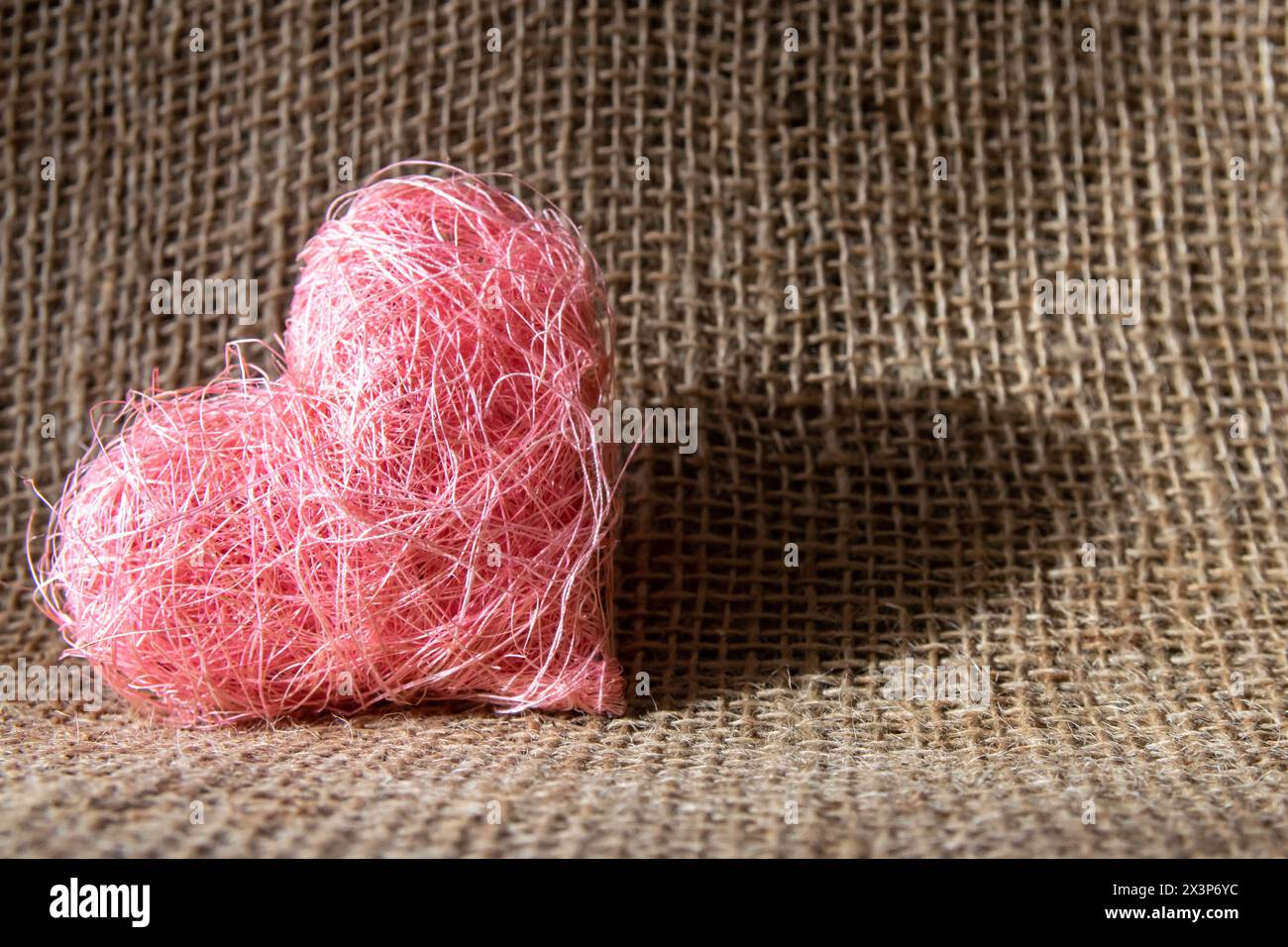 Beautiful pink heart shape made of material fabric on a rustic natural background. Concept of Valentine's day and romantic love. Stock Photo
