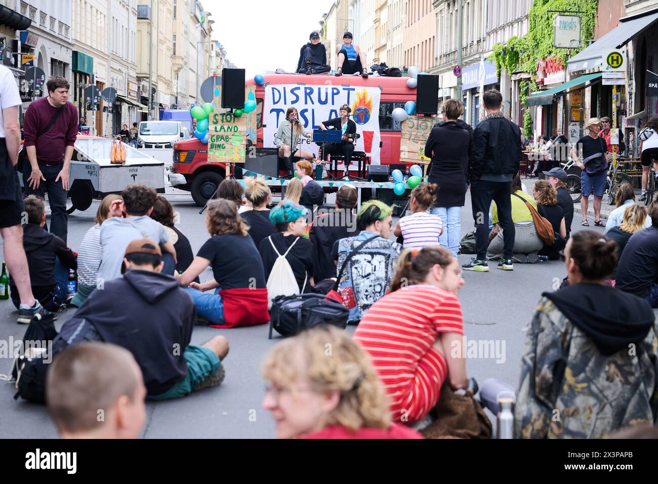 28 April 2024, Berlin: 'Disrupt Tesla' is written on a banner hanging from a minibus. Members of various alliances such as 'Tesla den Hahn abdrehen', 'A100 stoppen!' and 'Görlitz zaunfrei!' are celebrating a street party in Kreuzberg to demonstrate against Tesla and car policy. Photo: Annette Riedl/dpa Stock Photo