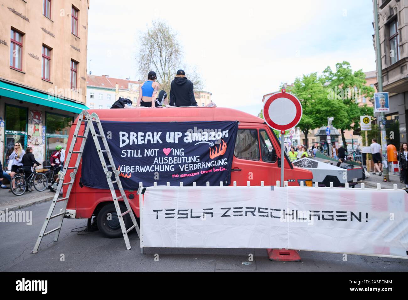 Berlin, Germany. 28th Apr, 2024. 'Smash Tesla!' and 'Break up amazon - still not loving exploitation - surveillance - displacement' are written on two banners at a protest against Tesla. Members of various alliances such as 'Tesla den Hahn abdrehen', 'A100 stoppen!' and 'Görlitz zaunfrei!' are celebrating a street party in Kreuzberg to demonstrate against Tesla and car policy. Credit: Annette Riedl/dpa/Alamy Live News Stock Photo