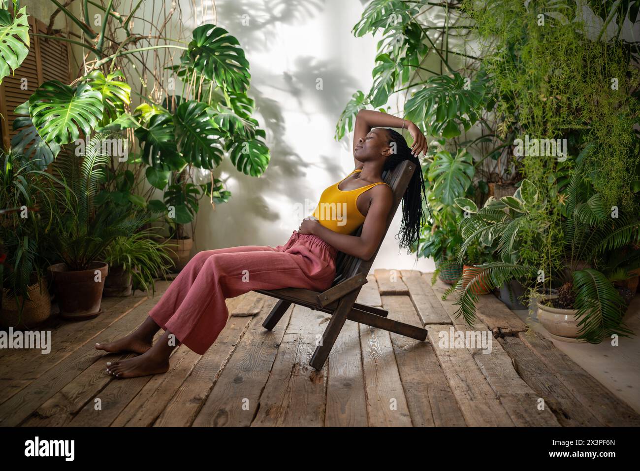 Relaxed black woman resting on chair with closed eyes among urban ...