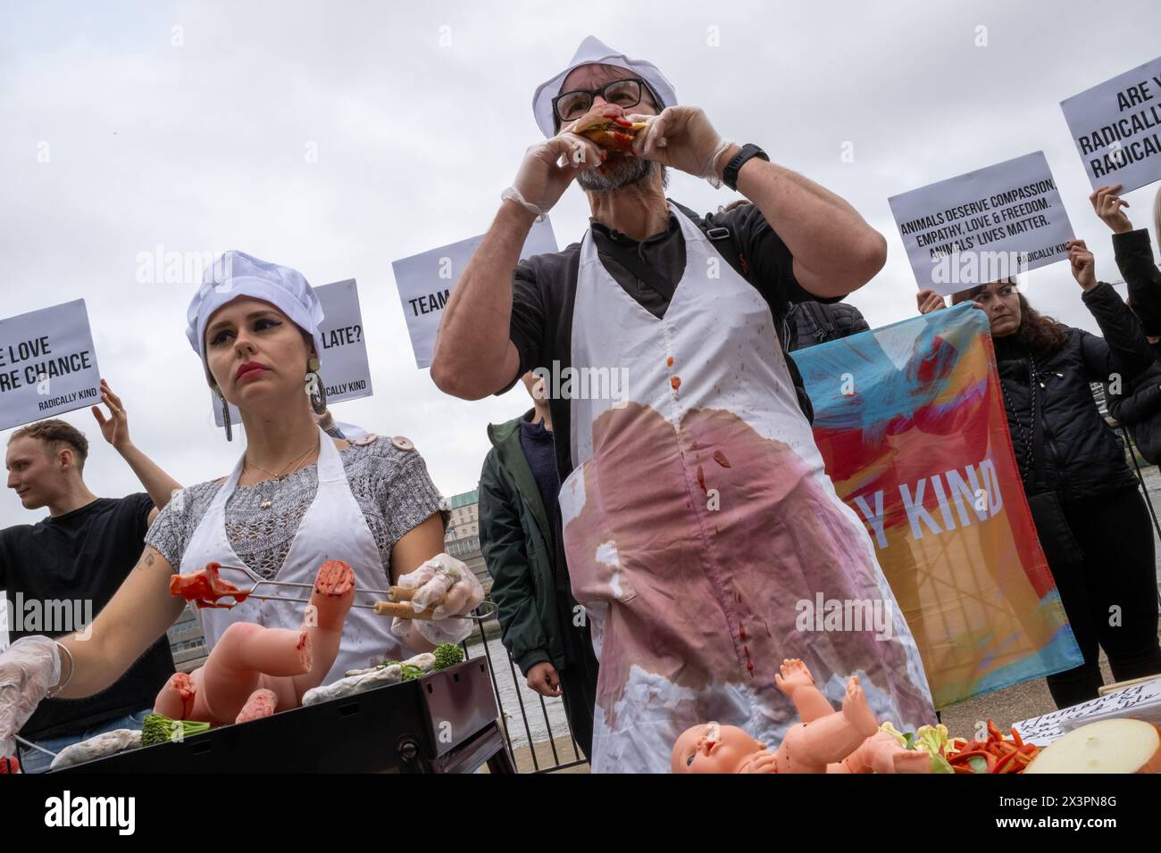 A vegan demonstrator pretends to eat a burger made of Human meat during the rally. Vegan group Radically Kind held a demonstration at the Tate Modern on the South Bank of the Thames. By showing graphic images they hope to convert meat eaters to veganism. Stock Photo