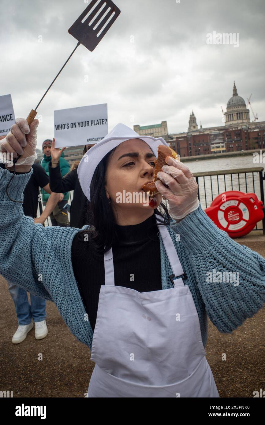 London, UK. 27th Apr, 2024. A vegan demonstrator pretends to eat a burger made of Human meat during the rally. Vegan group Radically Kind held a demonstration at the Tate Modern on the South Bank of the Thames. By showing graphic images they hope to convert meat eaters to veganism. (Photo by James Willoughby/SOPA Images/Sipa USA) Credit: Sipa USA/Alamy Live News Stock Photo