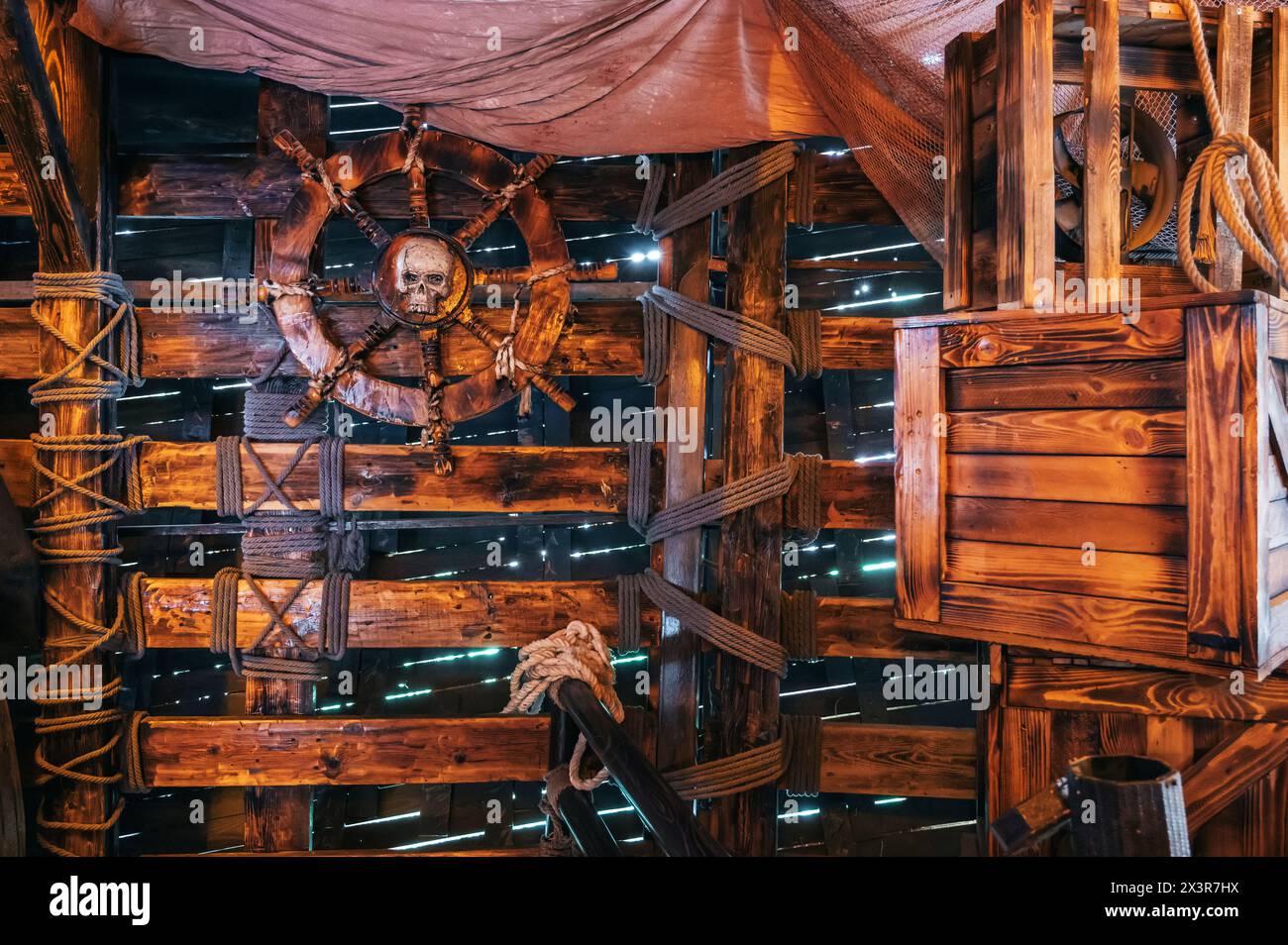 interior of captain cabin on an ancient medieval pirate ship with a wooden steering wheel with a pirate's skull emblem Stock Photo