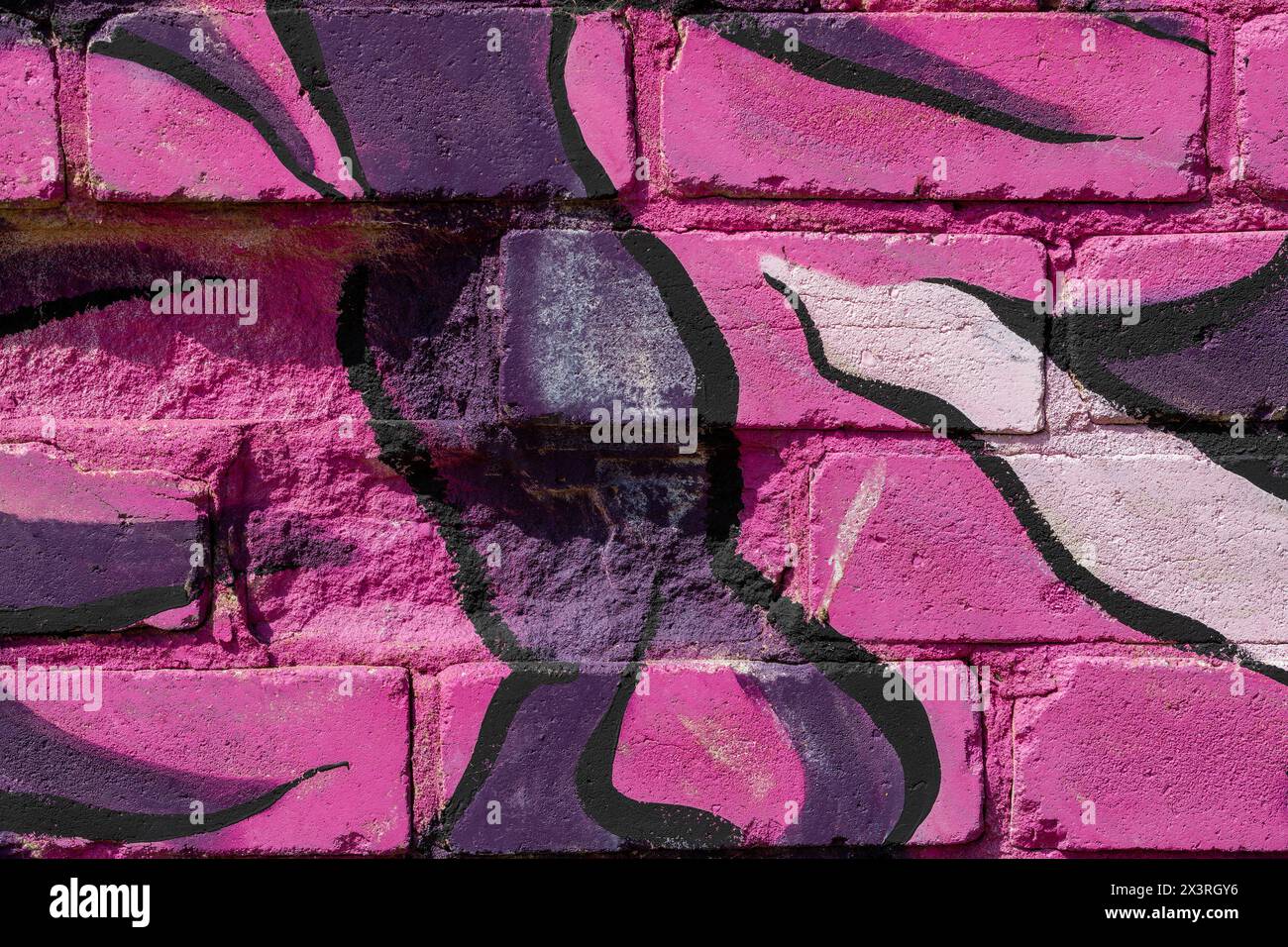The texture of a pink brick wall painted with different-toned pink and purple patterns. Stock Photo