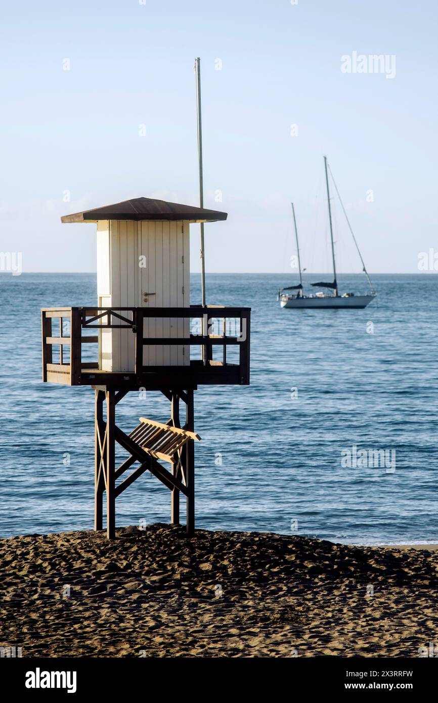 Lifeguard hut on the coast and a sailboat in the sea. Stock Photo