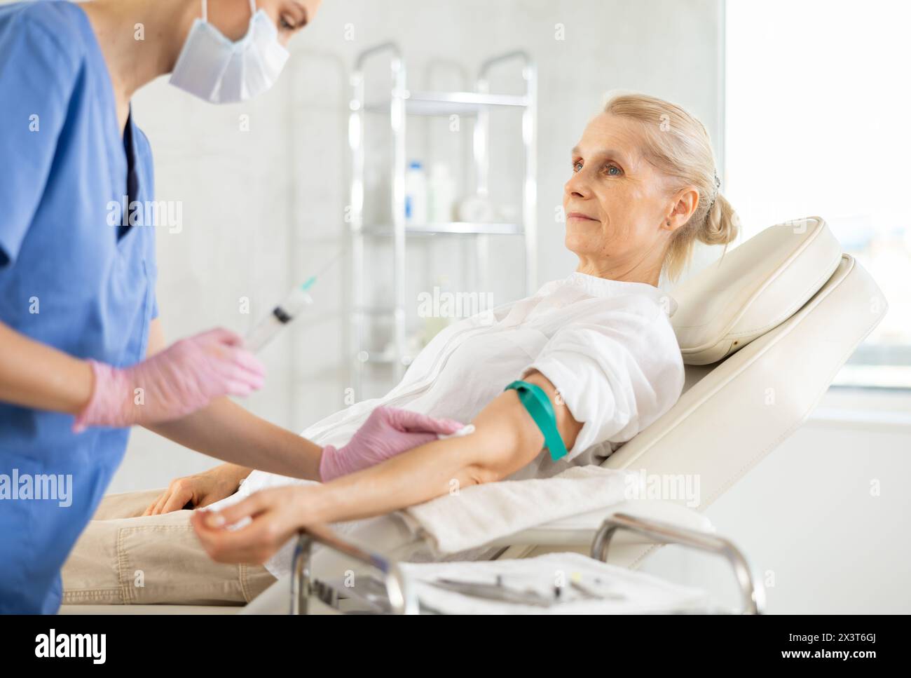 Doctor administering intravenous injection of vitamins to elderly