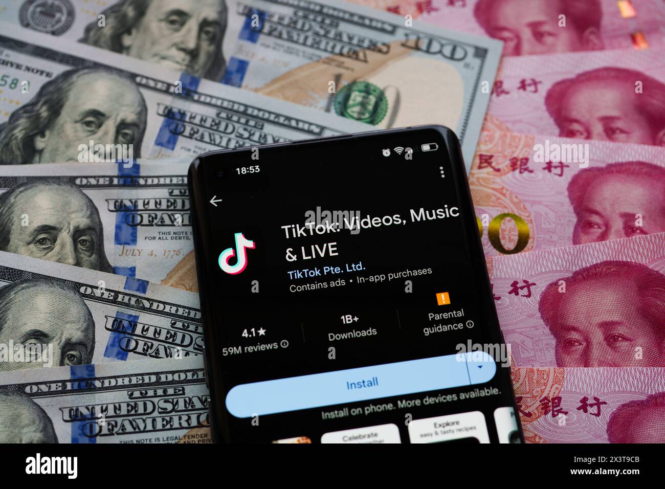 TikTok app seen on the screen of smartphone, which is placed on US dollars an Chinese Yuan banknotes. Stafford, United Kingdom, April 28, 2024 Stock Photo