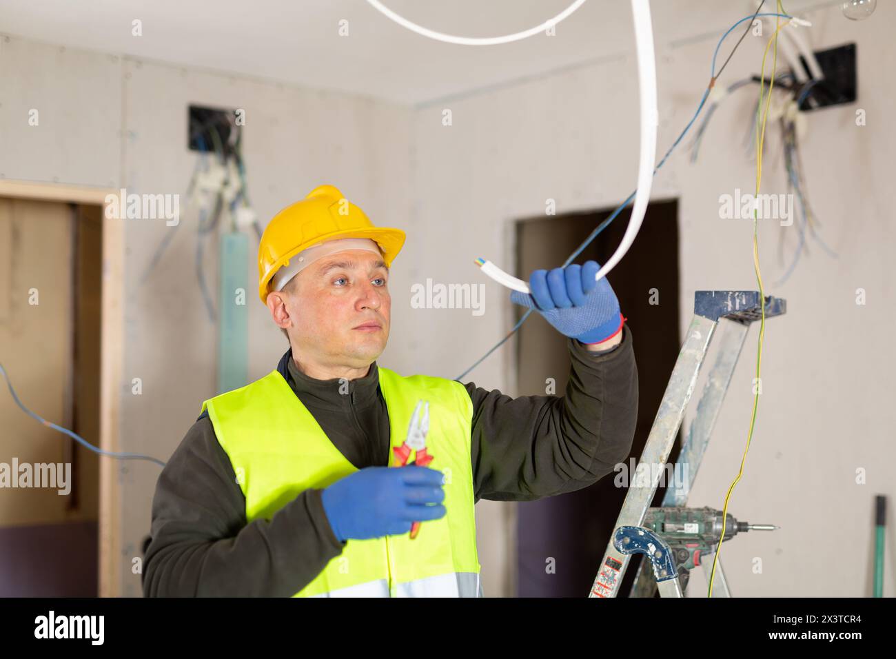 Electrician laying electric wires in building under construction Stock ...