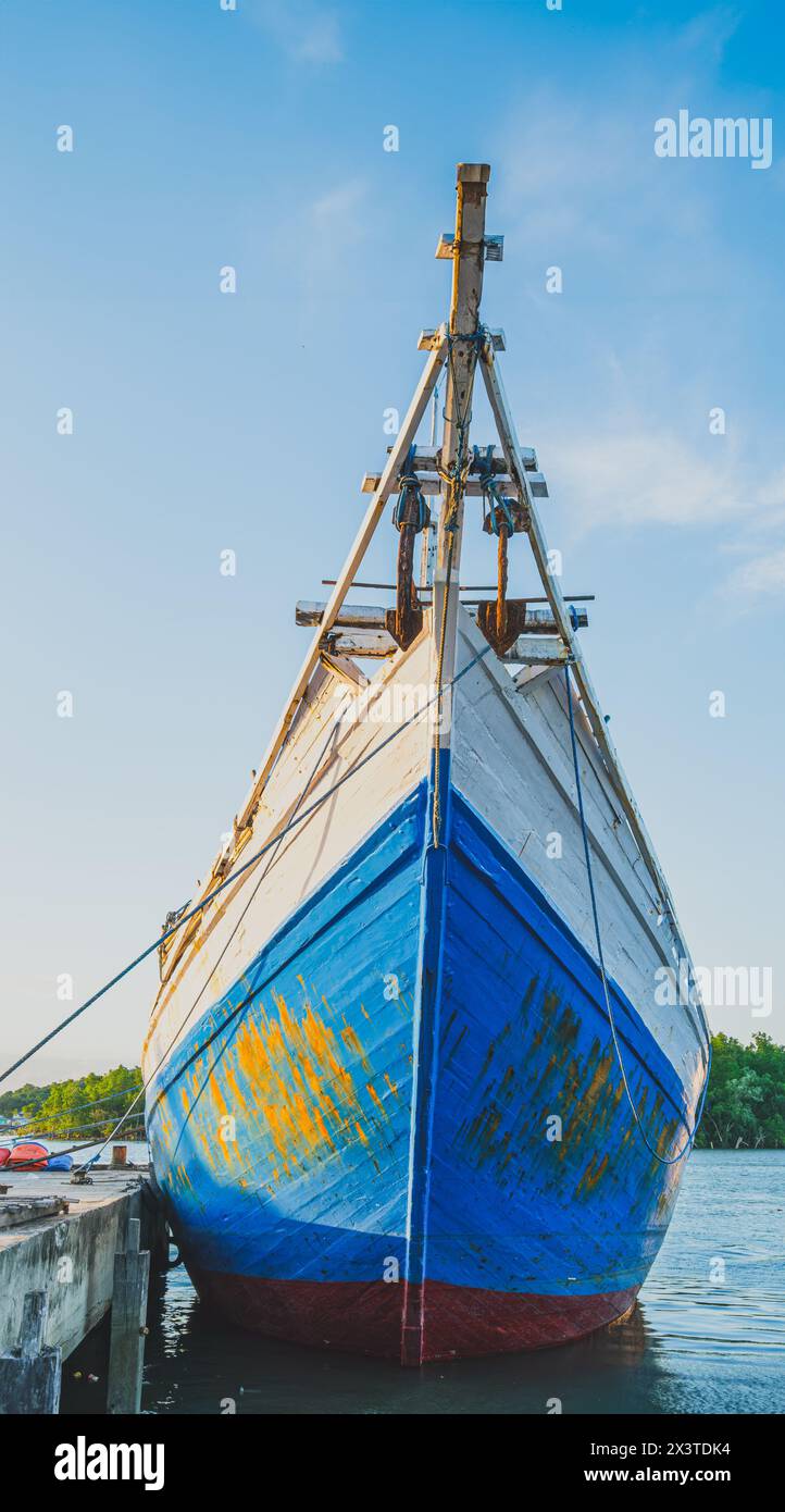 Balikpapan, Indonesia - April 12th, 2024. a classic blue and white Bugis schooner boat docked at a pier. The boat has a cabin with white trim and wind Stock Photo