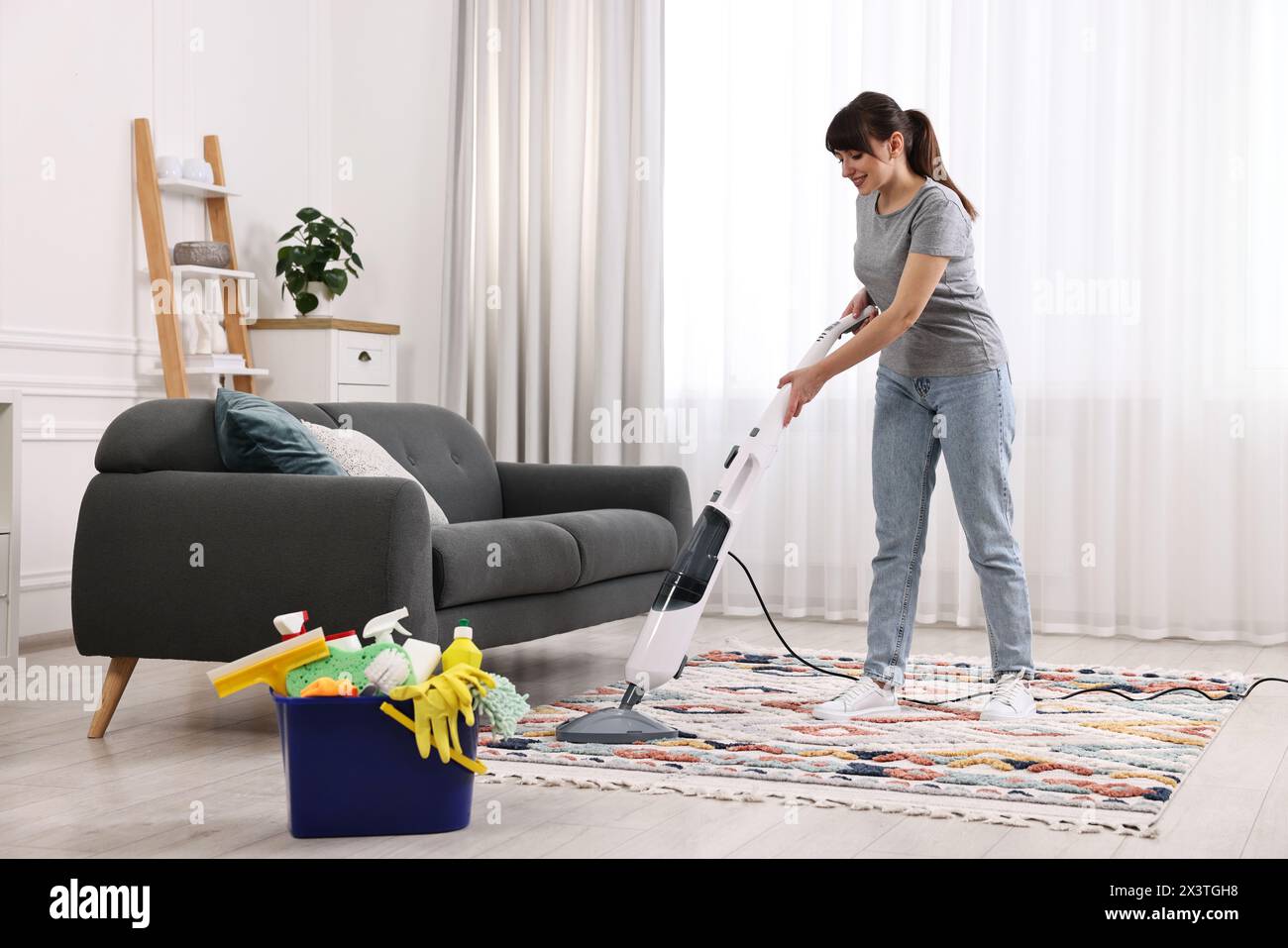 Happy young housewife vacuuming rug at home Stock Photo - Alamy