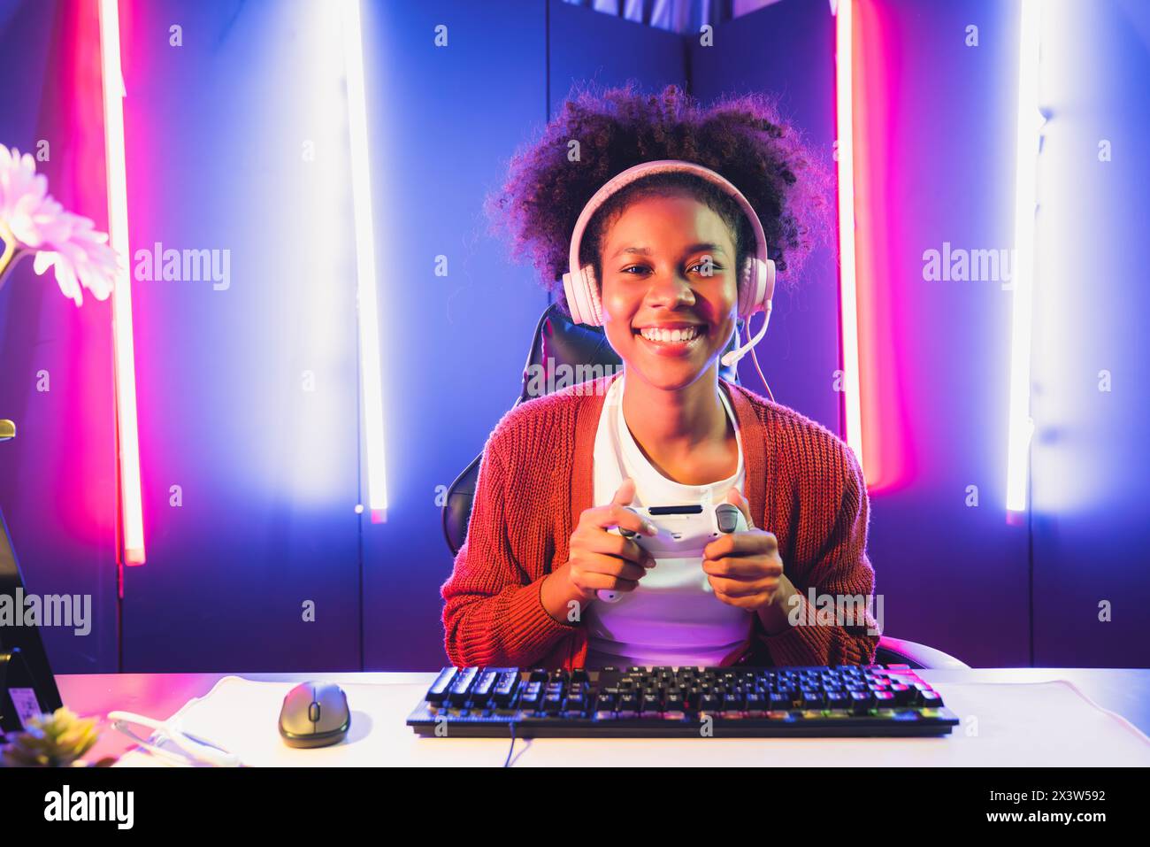 African American girl gaming streamer team winner playing online fighting with Esport wearing headphones in neon lighting room. Talking other players Stock Photo