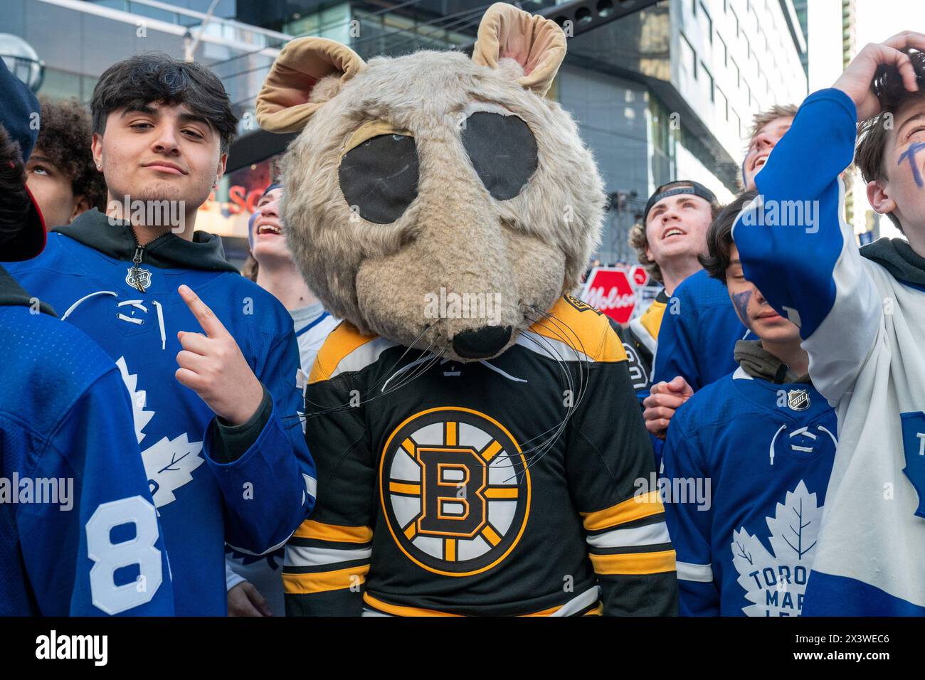 Fan dressed as Boston Bruins mouse at Maple Leaf Square outside Scotibank Arena, watching Round 1, Game 4 playoff game of Toronto Maple Leafs vs Boston Bruins playoff game on a giant screen. During Toronto Maple Leafs playoff games, Maple Leaf Square transforms into a sea of blue and white, echoing with the chants of passionate fans eagerly rallying behind their team's quest for victory. The electric atmosphere radiates anticipation and excitement, creating unforgettable memories for both die-hard supporters and casual observers alike. Stock Photo