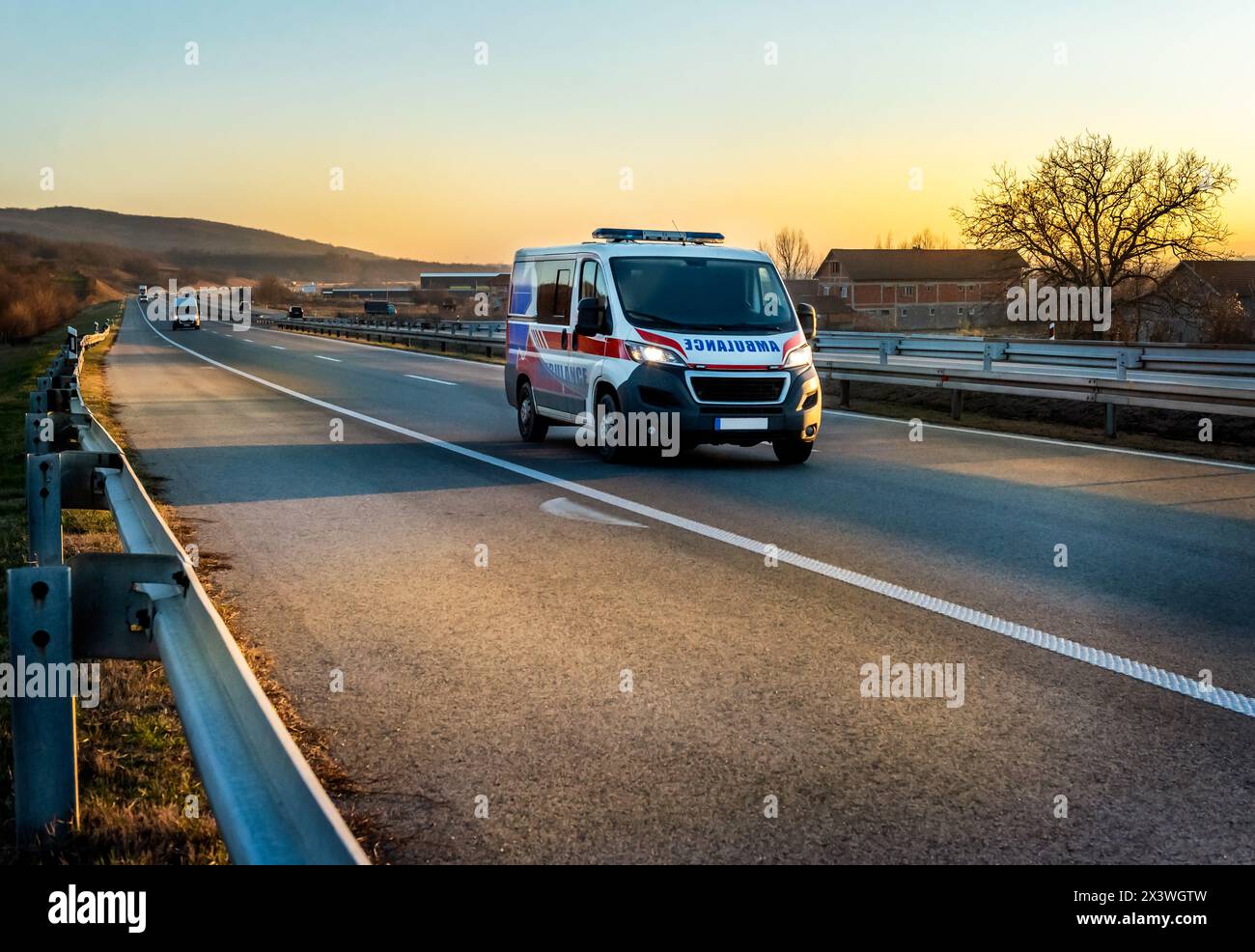 Ambulance van on highway at sunset. Ambulance car responding to the scene of an emergency. Stock Photo