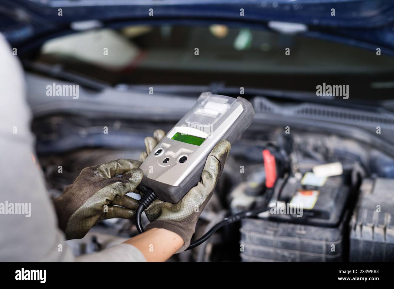 Female auto mechanic using diagnostic tool, scanner, running diagnostic