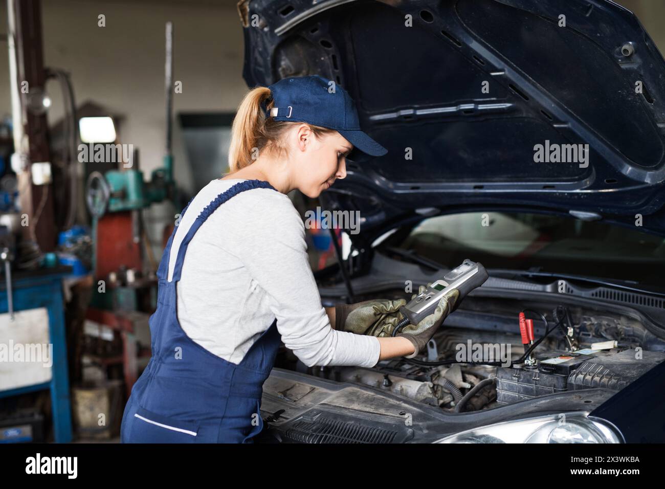 Female auto mechanic using diagnostic tool, scanner, running diagnostic