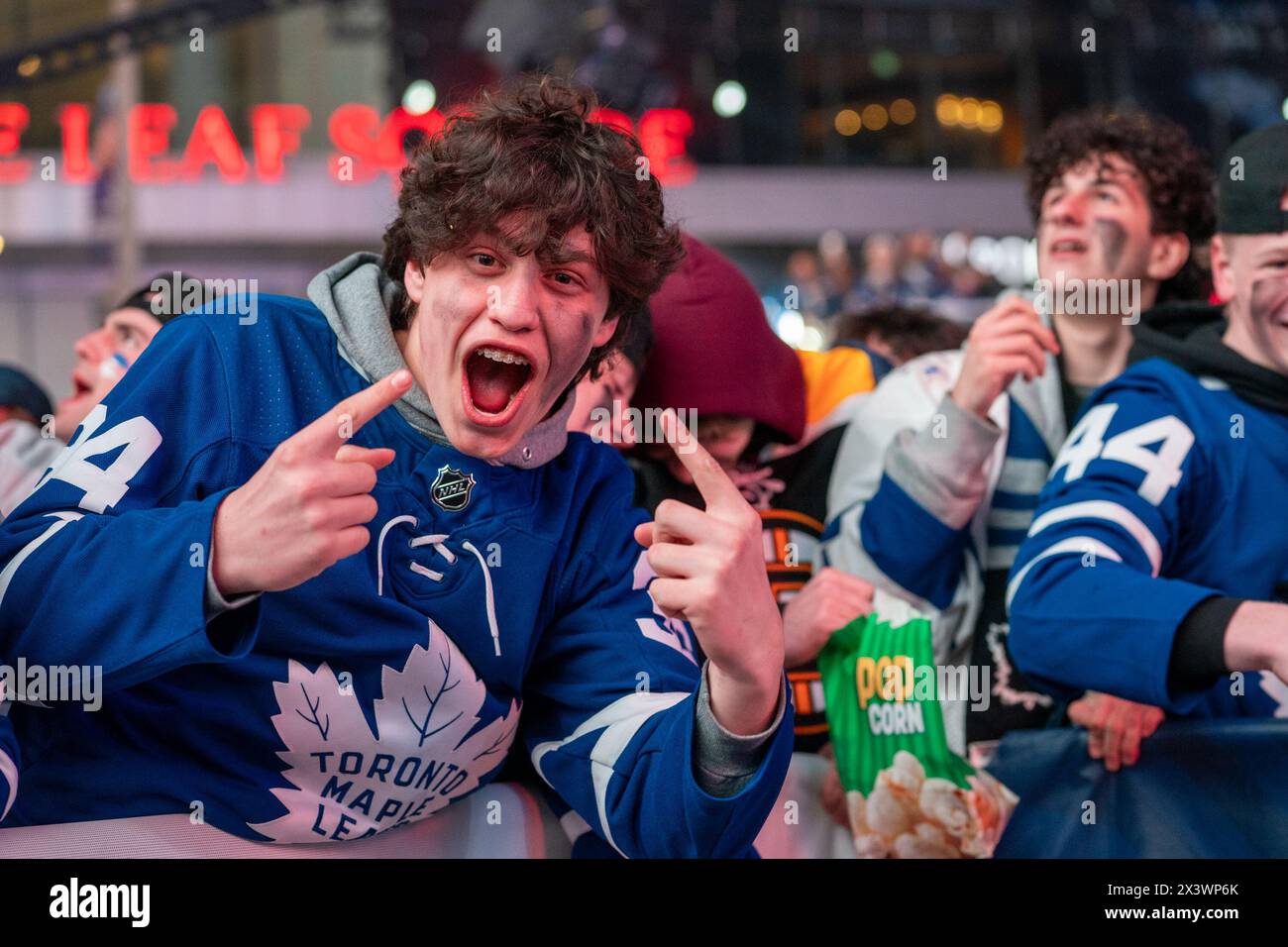 Fans watching the game on a giant screen react as the Toronto Maple Leafs score a goal against the Boston Bruins during Round 1, Game 4 at Maple Leaf Square outside Scotiabank Arena. During Toronto Maple Leafs playoff games, Maple Leaf Square transforms into a sea of blue and white, echoing with the chants of passionate fans eagerly rallying behind their team's quest for victory. The electric atmosphere radiates anticipation and excitement, creating unforgettable memories for both die-hard supporters and casual observers alike. Stock Photo