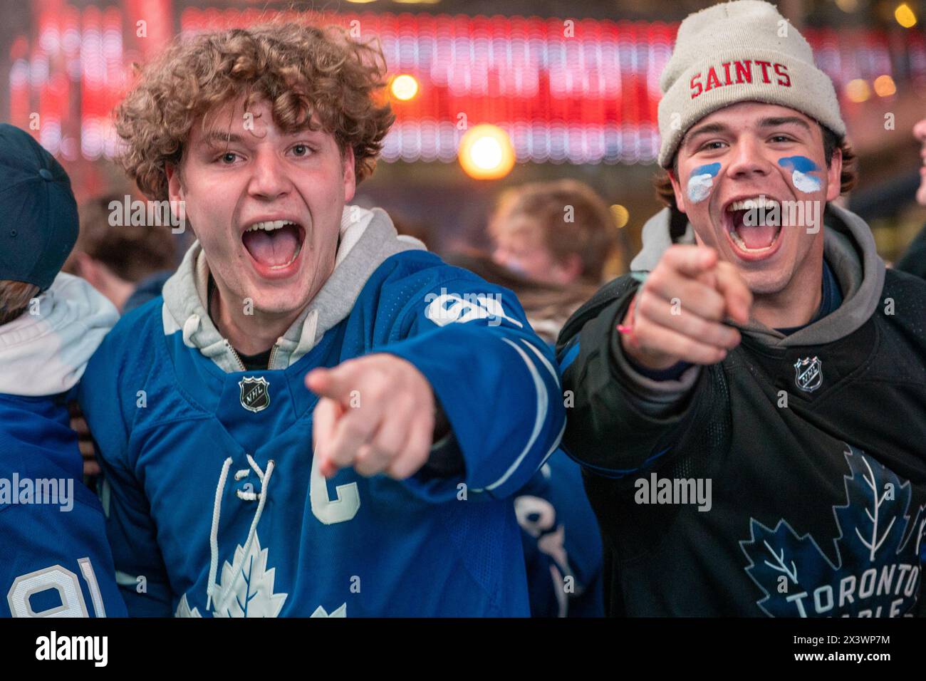 Fans watching the game on a giant screen react as the Toronto Maple Leafs score a goal against the Boston Bruins during Round 1, Game 4 at Maple Leaf Square outside Scotiabank Arena. During Toronto Maple Leafs playoff games, Maple Leaf Square transforms into a sea of blue and white, echoing with the chants of passionate fans eagerly rallying behind their team's quest for victory. The electric atmosphere radiates anticipation and excitement, creating unforgettable memories for both die-hard supporters and casual observers alike. Stock Photo