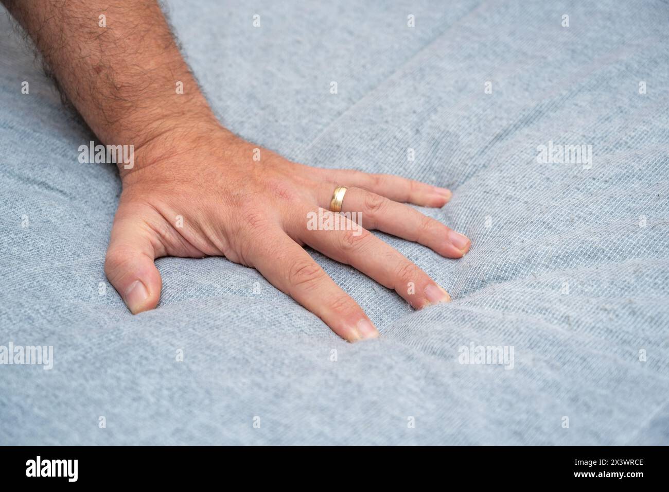 The man checks the quality and softness of the new mattress he will buy by pressing it with his hand Stock Photo