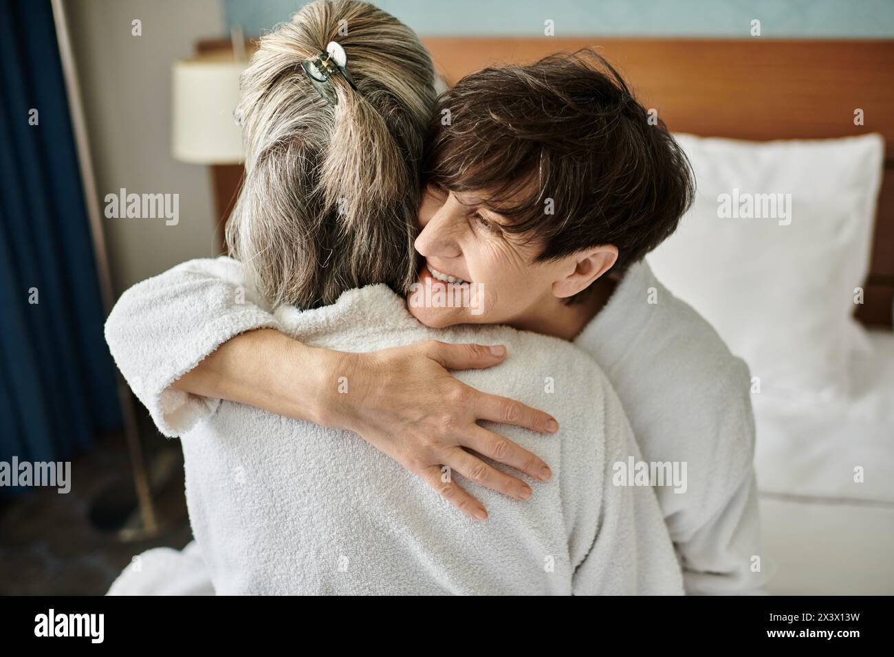 Tender moment between a loving senior lesbian couple in a hotel. Stock Photo