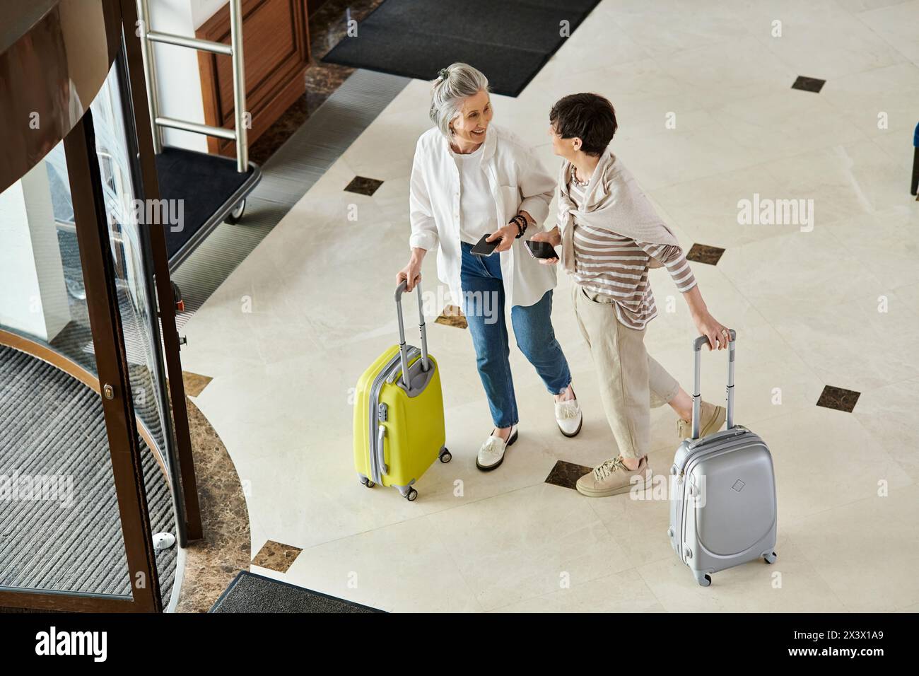 Loving senior lesbian couple standing with their luggage in a hotel. Stock Photo
