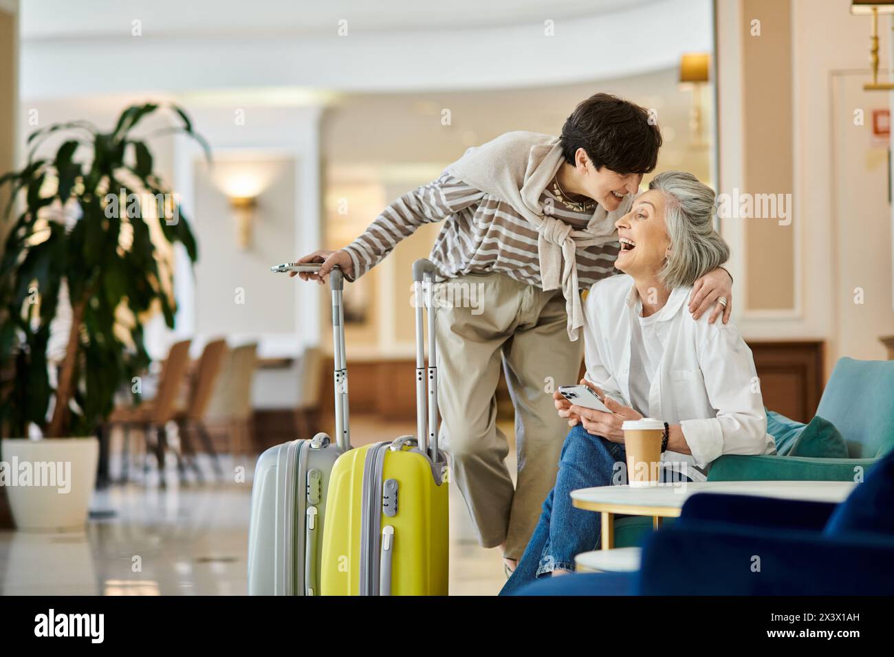 Senior lesbian couple with a suitcase in a hotel hallway. Stock Photo