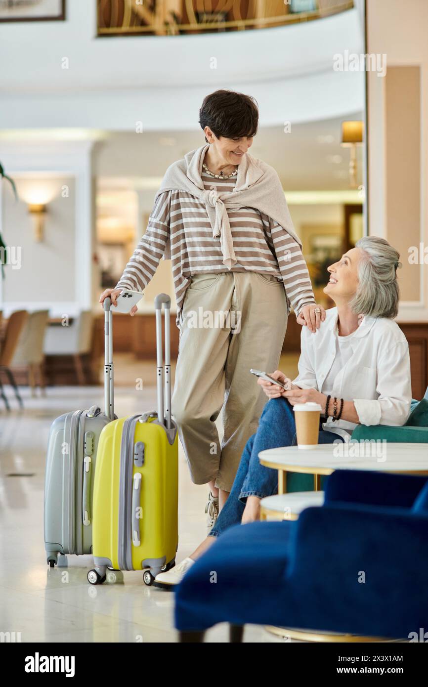 A senior lesbian couple, one with luggage, standing together. Stock Photo