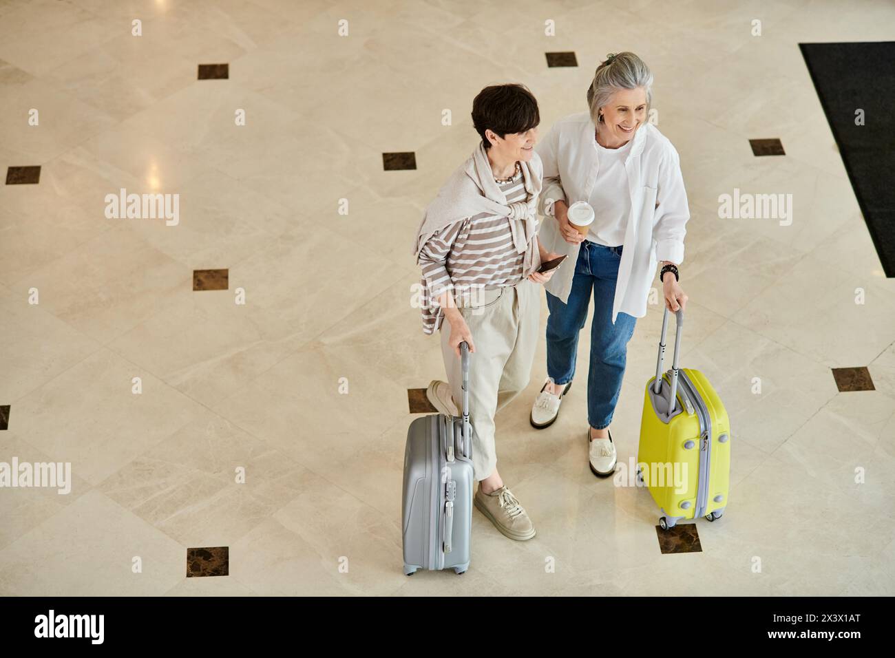 Senior lesbian couple standing with luggage, ready for their journey. Stock Photo