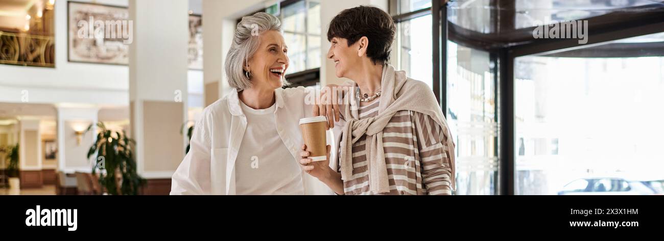 A tender moment between a loving senior lesbian couple, standing together in a hotel. Stock Photo