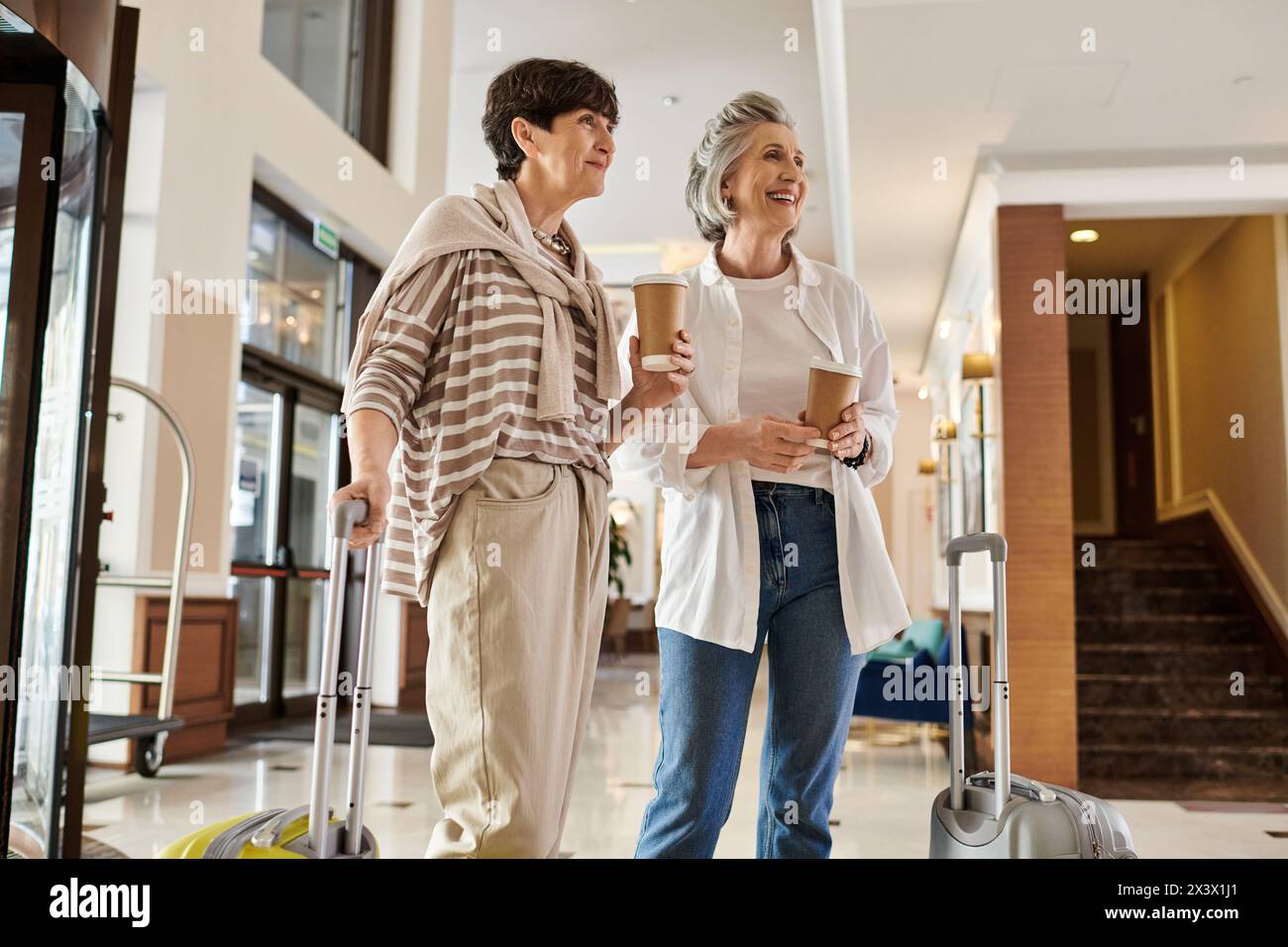 A senior lesbian couple stands with luggage, ready for adventure. Stock Photo