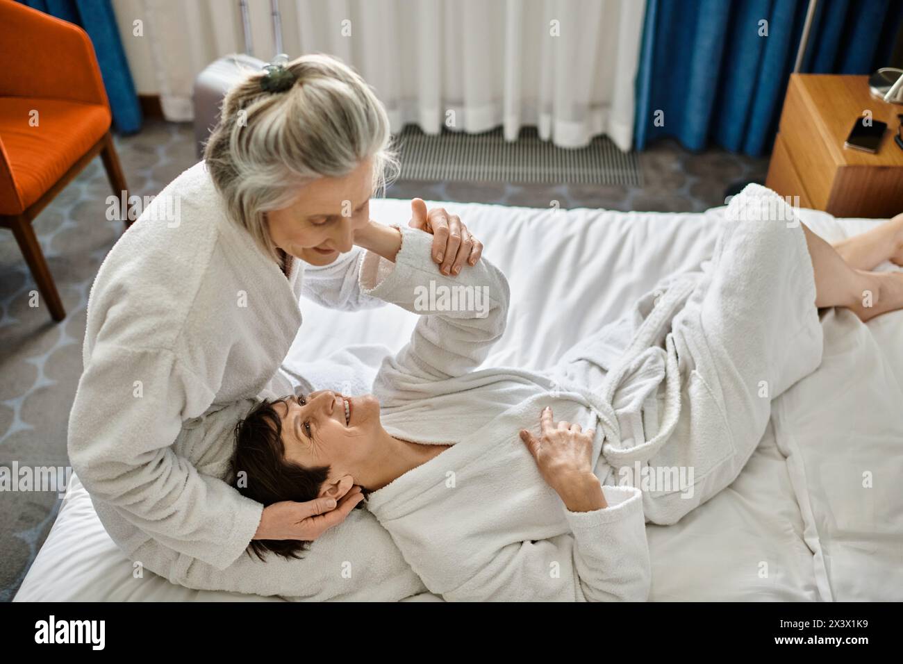 Senior lesbian couple tenderly laying together on a bed. Stock Photo