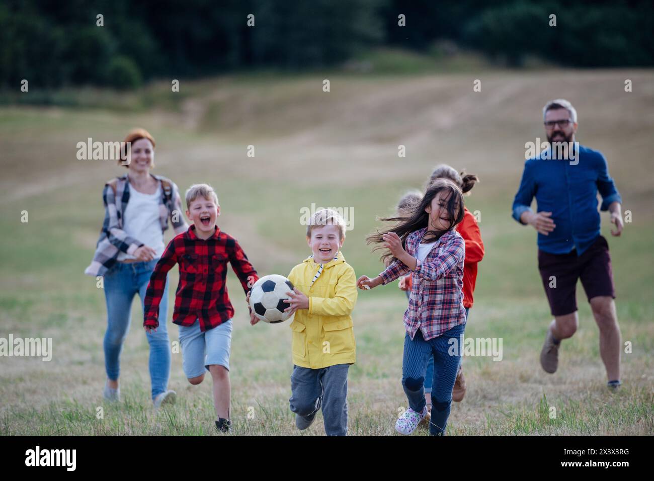 Young students playing with teacher outdoors, in nature, during field ...