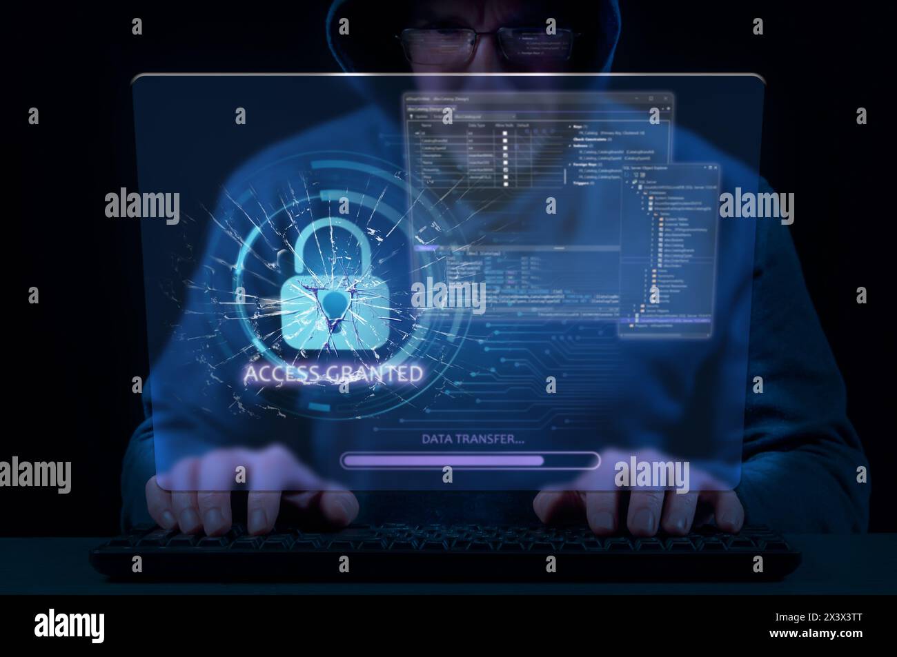 Man in hood on dark background uses keyboard and virtual screen to break cybersecurity system Stock Photo