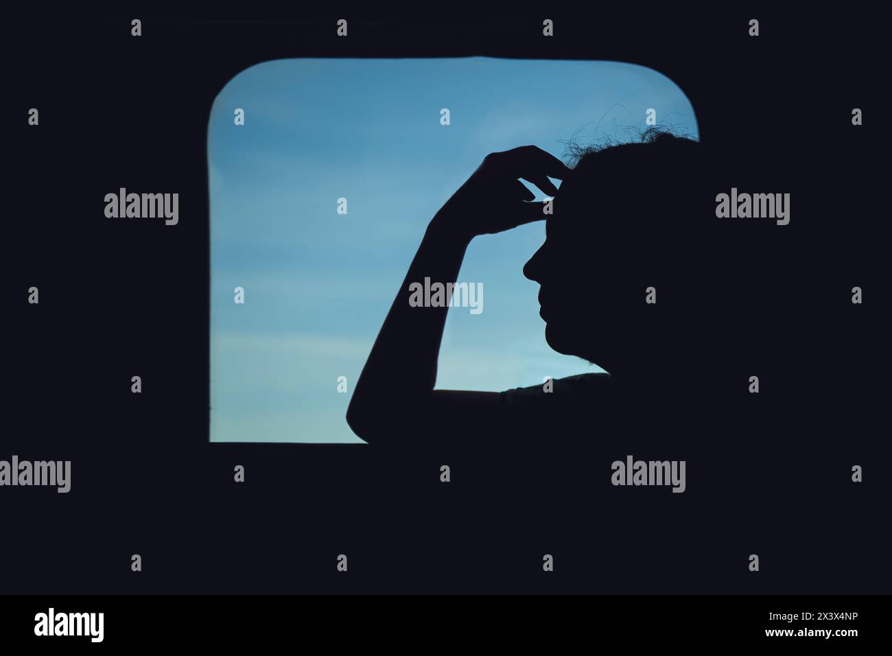 Silhouette of adult female by the train window, worried woman traveling by train, back lit Stock Photo